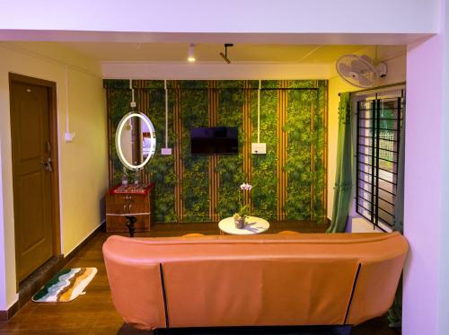 a living room with a couch and a green wall at Cocobaba Farmstay in Kumta