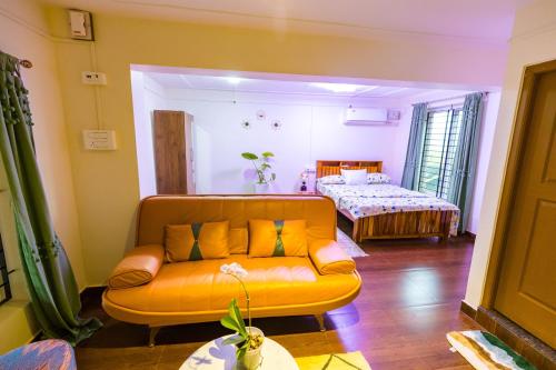 an orange couch in a living room with a bed at Cocobaba Farmstay in Kumta