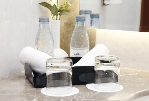 two glasses and bottles on a counter with towels at MADEN Al Rawda مادن الروضة in Al Madinah