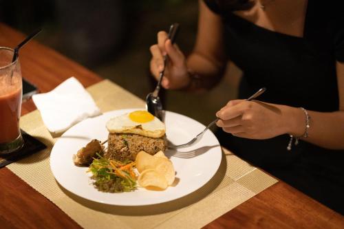 a woman sitting at a table with a plate of food at The Central Lovina Hotel & Restaurant in Lovina