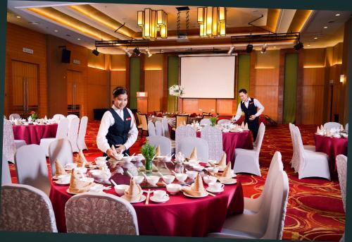 two people standing in a room with tables and chairs at Grand Lexis Port Dickson in Port Dickson