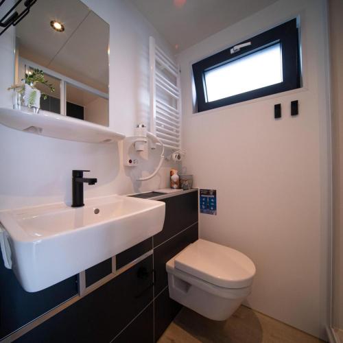 a bathroom with a sink and a toilet and a window at Houseboat Heeg on the Water | 4 people in Heeg