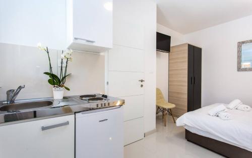 a small white kitchen with a sink and a bed at Apartments Bernardeta 1 in Baška