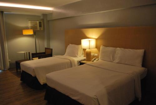 a hotel room with two beds and a lamp at Cebu Grand Hotel in Cebu City
