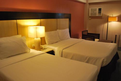 a hotel room with two beds and a lamp at Cebu Grand Hotel in Cebu City