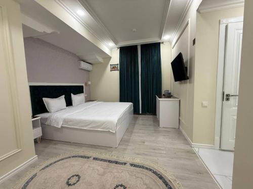 a bedroom with a large white bed and a television at Beksaroy in Samarkand