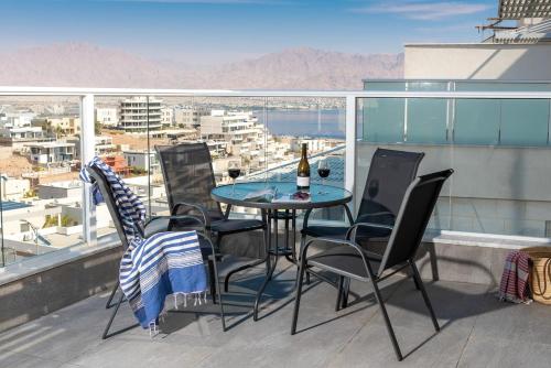 a table and chairs on a balcony with a bottle of wine at Penthouse Salomon cliffs in Eilat