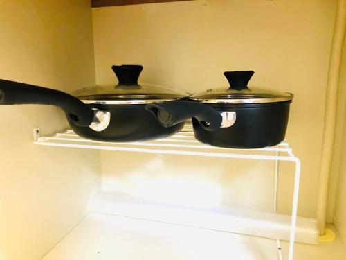 two pans sitting on a shelf in a kitchen at 三の丸Stay in Kumamoto