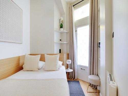 une chambre avec un lit blanc et une fenêtre dans l'établissement Charming Apt - 1BD 4P - Invalides Bon Marché, à Paris
