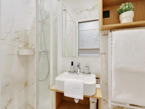 une salle de bain blanche avec un lavabo et une douche dans l'établissement Charming Apt - 1BD 4P - Invalides Bon Marché, à Paris