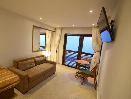 a living room with a couch and a flat screen tv at Arca do Noah in Jericoacoara