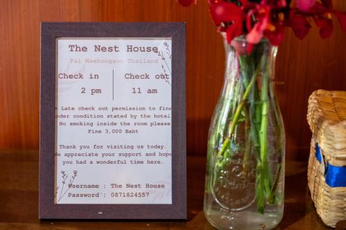 a sign next to a vase with flowers on a table at The Nest House in Pai