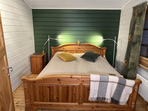 a bedroom with a wooden bed with green walls at Chalet Pellonranta 1 in Pello