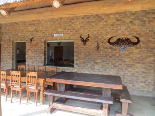 a wooden table and chairs in front of a brick wall at Isilwane Bush Camp in Pretoria