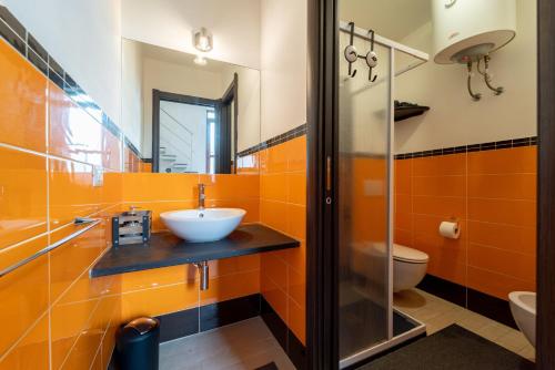 an orange bathroom with a sink and a toilet at Casa Violante in Alghero