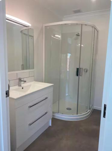 a white bathroom with a shower and a sink at On The Beach in Napier