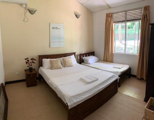 a bedroom with two beds and a window at Tamarind Hill Country Escape in Digana