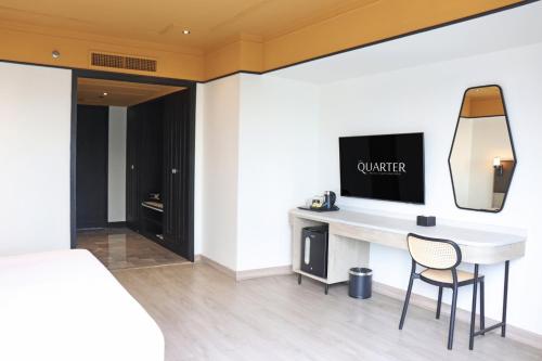 a bedroom with a desk with a television on a wall at The Quarter Saphankhwai by UHG in Bangkok