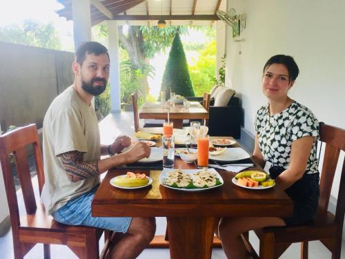 two men sitting at a wooden table with food at Swan Lake Habarana in Habarana