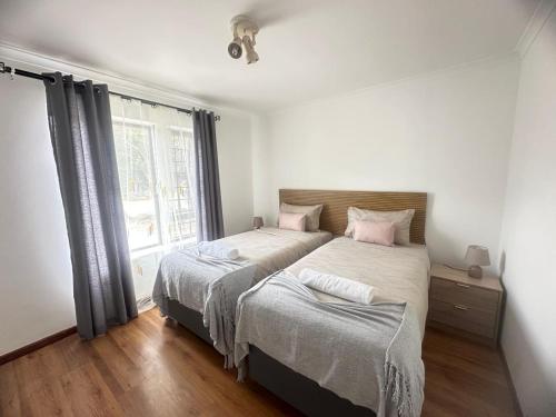 ケープタウンにあるMBCholidayhouseのベッド2台と窓のある寝室