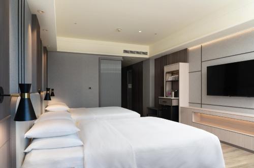 a bedroom with four white beds and a flat screen tv at E-DA Royal Hotel in Dashu