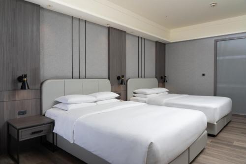 two beds in a hotel room with white sheets at E-DA Royal Hotel in Dashu
