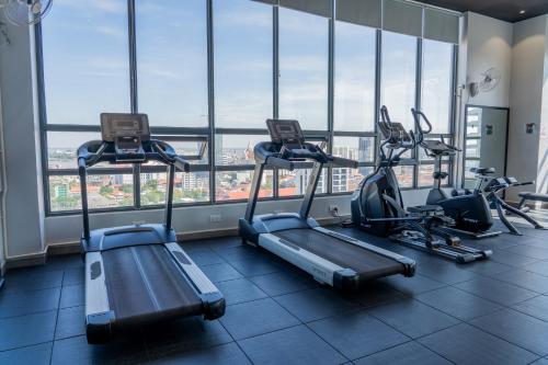 a gym with two treadmills and ellipticals in front of windows at Parc21 Luxury Boutique Hotel in Phnom Penh