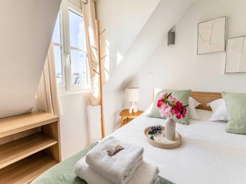 a white bedroom with a bed with a vase of flowers at Studio COSY in the heart of Paris - Mobility lease in Paris