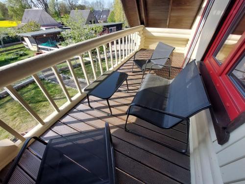 a balcony with chairs and tables and a red door at Blockhaus Elana in Möllenhagen