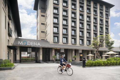 a man riding a bike in front of a building at Modena by Fraser Vinh Yen in Yen