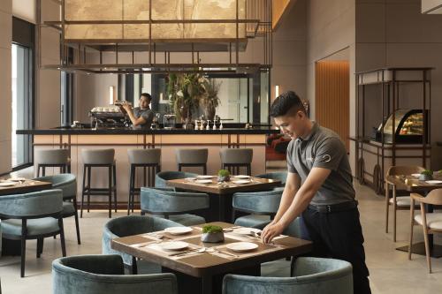 a man standing at a table in a restaurant at Modena by Fraser Vinh Yen in Yen