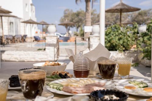 a table with plates of food and drinks on it at Christiana Hotel in Ambelas