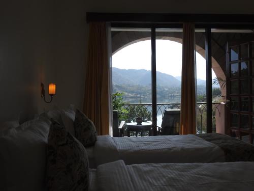 a hotel room with two beds and a large window at Saket LOAK in Udaipur