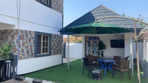 a patio with a table and a green umbrella at 501 Aparthotel in Akure