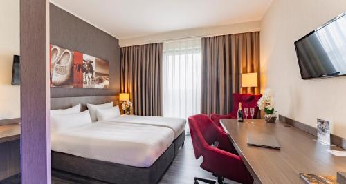 a hotel room with a bed and a desk at PLAZA Premium Grand Winston in Rijswijk