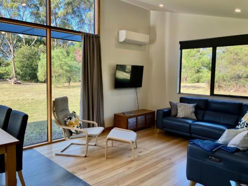 a living room with a blue couch and a tv at Salt House Brand New Bayside Accommodation in Bream Creek