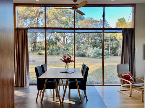 a dining room with a table and chairs and a large window at Salt House Brand New Bayside Accommodation in Bream Creek