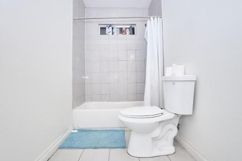 a white bathroom with a toilet and a bath tub at Blue Private Room near BMO Stadium USC and K-Town in Los Angeles