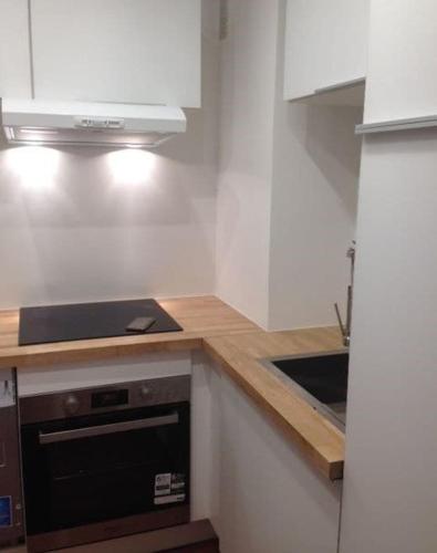 - une cuisine avec des placards blancs et une cuisinière noire dans l'établissement Boramar Cosy appartement pour 4 pers - Terrasse vue mer, à Canet