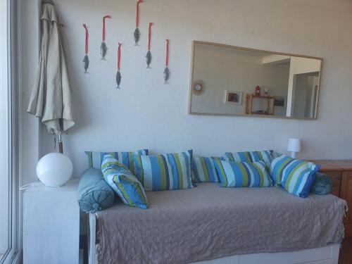 Cette chambre comprend un canapé avec des oreillers et un miroir. dans l'établissement Boramar Cosy appartement pour 4 pers - Terrasse vue mer, à Canet
