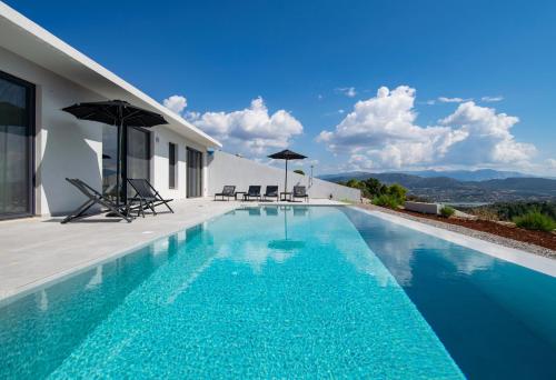 a swimming pool with blue water in front of a house at Pentacle Villas in Lefkada Town