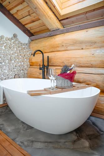 a white bath tub in a room with a wooden wall at Prosilva House Banffy 2 in Topliţa