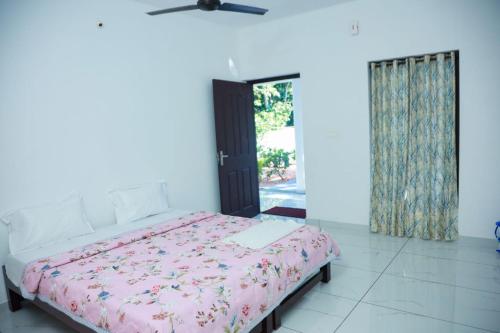 a bedroom with a bed with a pink comforter at Marari Arattukulam Villa in Mararikulam