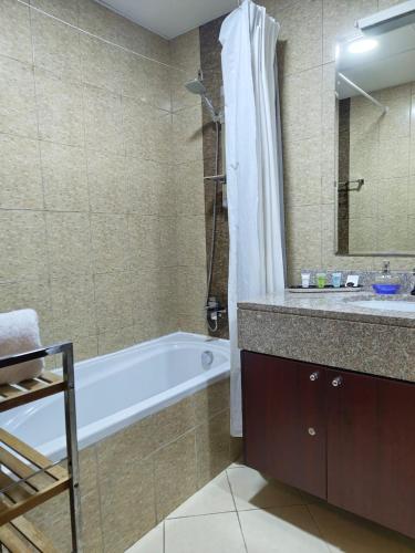 a bathroom with a bath tub and a sink at Studio in the heart of Sports City -great view & amenities! in Dubai