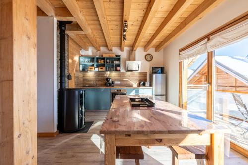 une cuisine avec une table en bois et une grande fenêtre dans l'établissement Chalet Hameau de Comborciere - Station La Toussuire, à La Toussuire