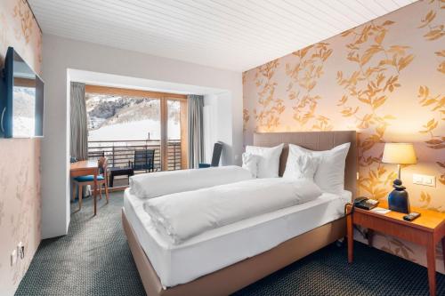 a hotel room with a bed and a desk at Le Bristol Leukerbad in Leukerbad
