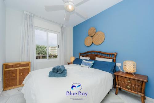 Dormitorio azul chico con cama y ventana en Palm Beach Apartment, en La Herradura