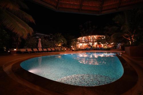 a swimming pool at night with a building in the background at Argo by Trance in Dabolim