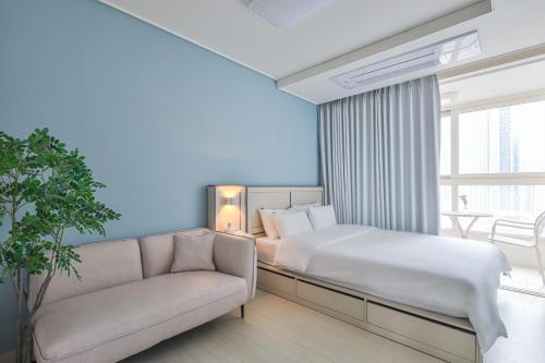 a bedroom with a bed and a couch and a window at Landmark Stay in Songdo in Incheon