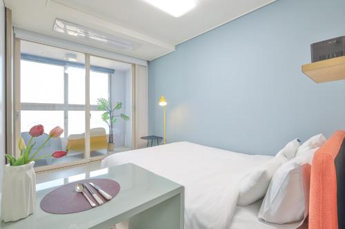 a white bedroom with a white bed and a window at Landmark Stay in Songdo in Incheon
